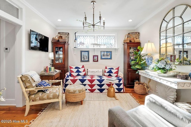 living area with hardwood / wood-style flooring, crown molding, and an inviting chandelier