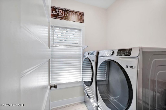 clothes washing area with separate washer and dryer, a wealth of natural light, and light tile patterned flooring