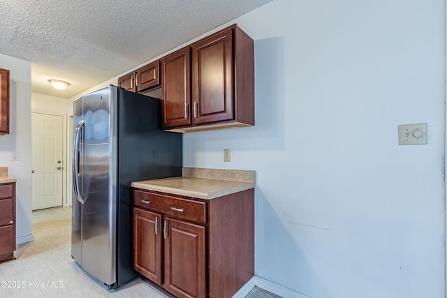 kitchen featuring stainless steel refrigerator with ice dispenser and a textured ceiling