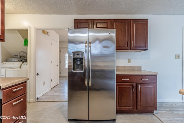 kitchen featuring a textured ceiling, stainless steel fridge with ice dispenser, independent washer and dryer, and light wood-type flooring