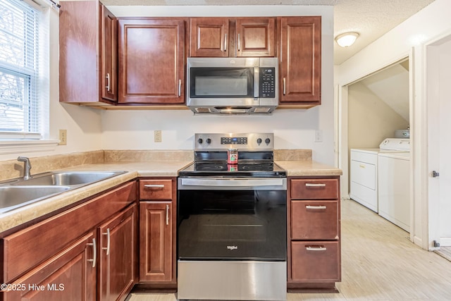 kitchen with washing machine and dryer, a wealth of natural light, stainless steel appliances, and sink