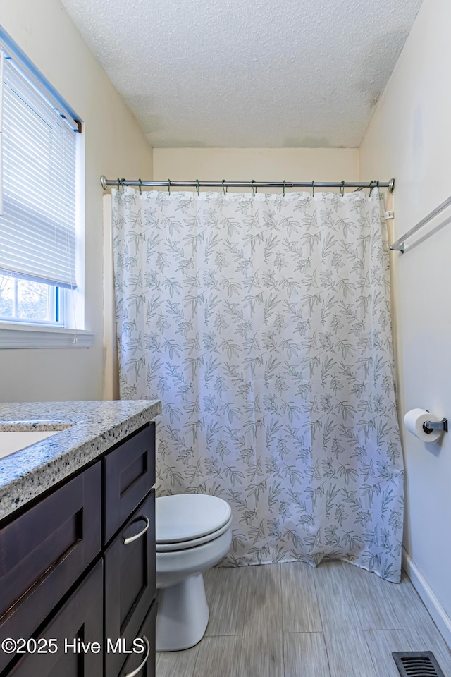 bathroom with a textured ceiling, toilet, and vanity