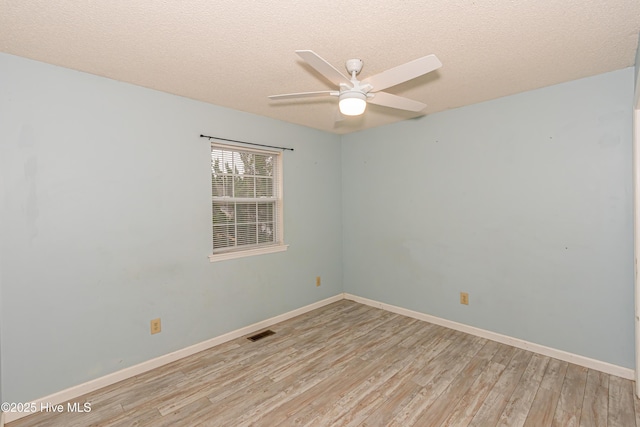 empty room featuring ceiling fan, light wood-type flooring, and a textured ceiling