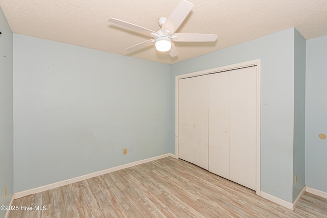 unfurnished bedroom featuring ceiling fan, a closet, a textured ceiling, and light hardwood / wood-style flooring