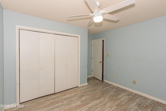 unfurnished bedroom with ceiling fan, a textured ceiling, a closet, and light wood-type flooring