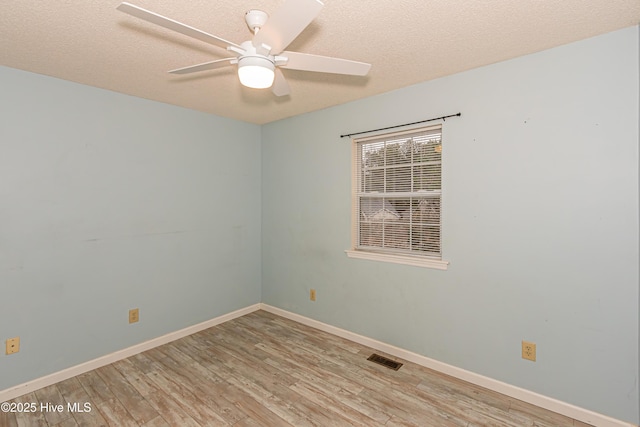 empty room featuring ceiling fan, light wood-type flooring, and a textured ceiling