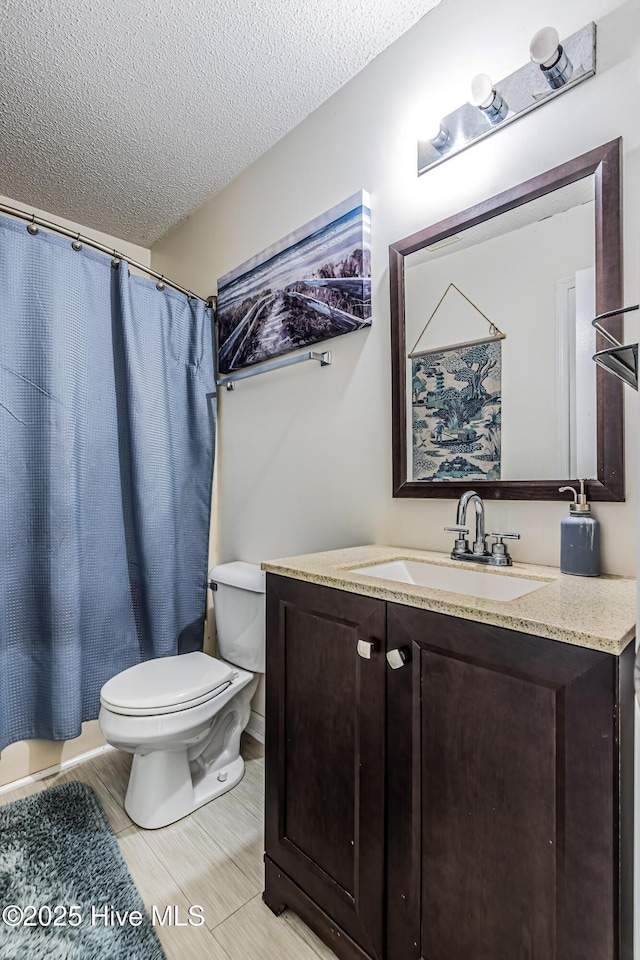 bathroom with a textured ceiling, toilet, and vanity