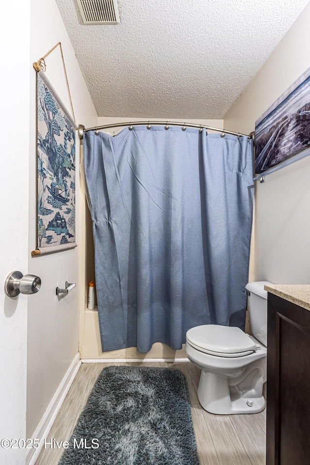 full bathroom featuring a textured ceiling, hardwood / wood-style floors, vanity, toilet, and shower / bath combo with shower curtain