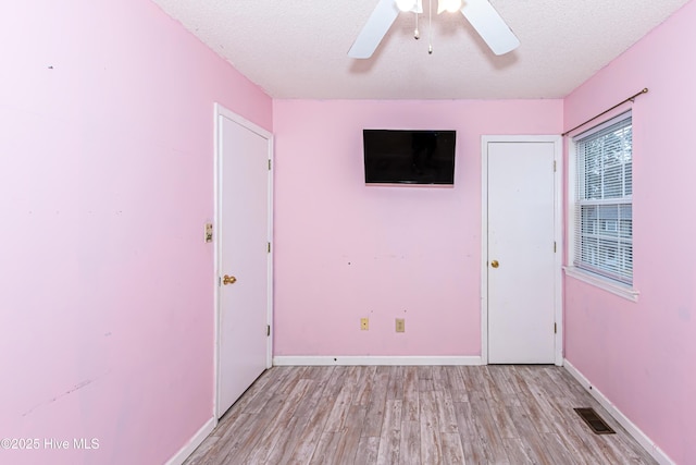 unfurnished bedroom with ceiling fan, light hardwood / wood-style floors, and a textured ceiling