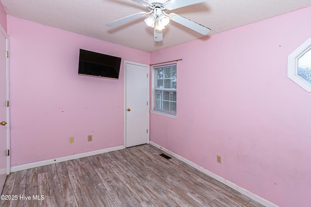 unfurnished room featuring ceiling fan, a textured ceiling, and light hardwood / wood-style flooring