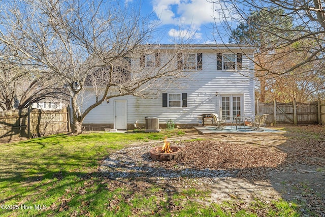 rear view of property featuring central AC unit, a yard, a fire pit, and a patio