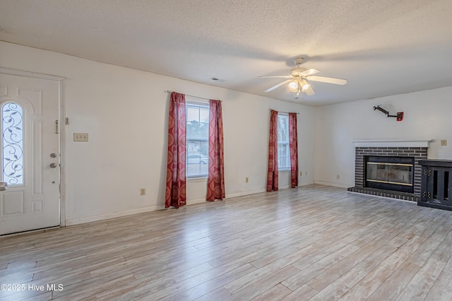 unfurnished living room with ceiling fan, a textured ceiling, light hardwood / wood-style flooring, and a fireplace