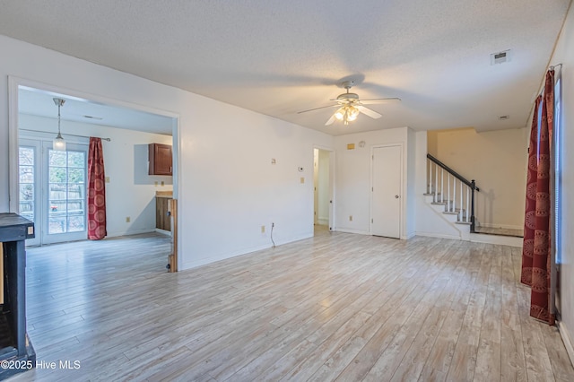 unfurnished living room featuring light wood-type flooring, ceiling fan, and a textured ceiling