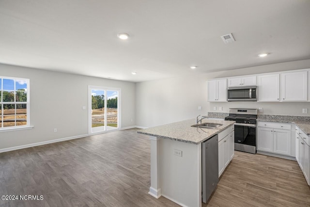 kitchen with white cabinetry, stainless steel appliances, an island with sink, light hardwood / wood-style floors, and sink