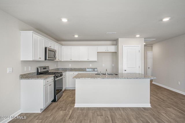 kitchen featuring stainless steel appliances, white cabinetry, and a kitchen island with sink