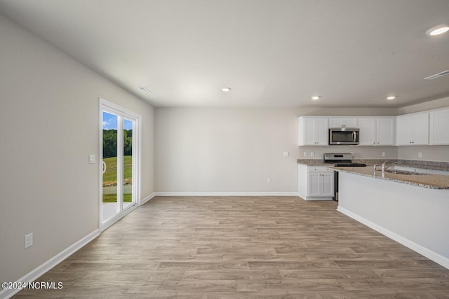 kitchen with sink, light wood-type flooring, light stone countertops, appliances with stainless steel finishes, and white cabinets