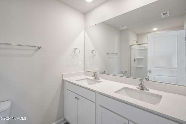 bathroom featuring toilet, vanity, and a shower with shower door