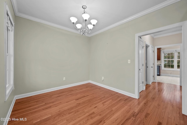 empty room featuring light wood-type flooring, a notable chandelier, and ornamental molding