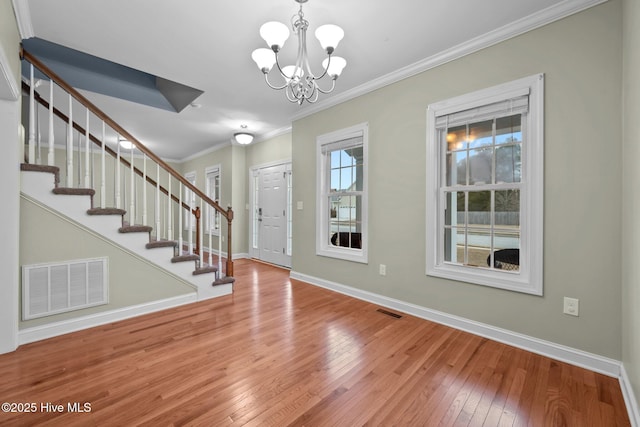 foyer featuring ornamental molding, hardwood / wood-style floors, and a notable chandelier