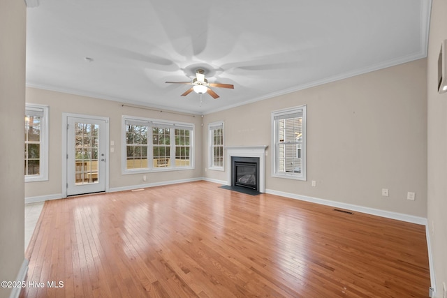 unfurnished living room with ceiling fan, ornamental molding, and light wood-type flooring