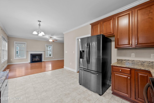 kitchen with light stone counters, stainless steel refrigerator with ice dispenser, pendant lighting, and ornamental molding