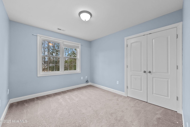 unfurnished bedroom with light colored carpet and a closet