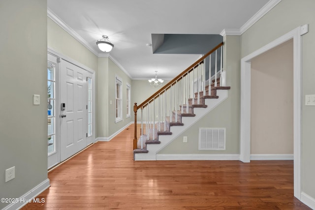 foyer entrance featuring wood-type flooring, a notable chandelier, and ornamental molding