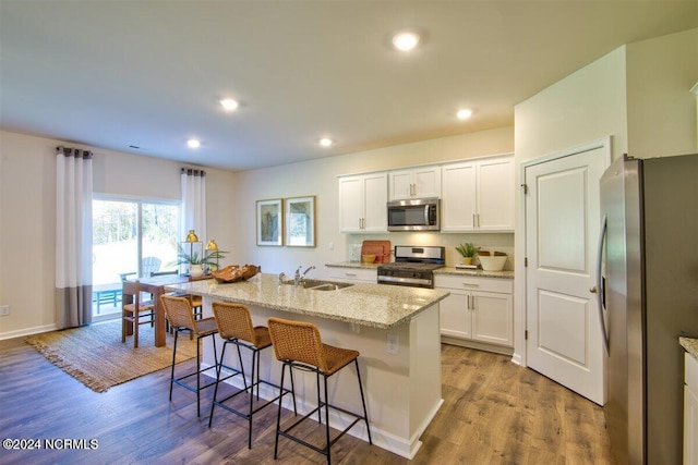 kitchen with light hardwood / wood-style floors, a center island with sink, appliances with stainless steel finishes, white cabinets, and sink