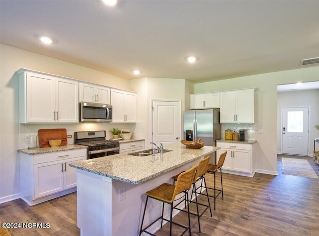 kitchen with appliances with stainless steel finishes, sink, white cabinetry, and a center island with sink