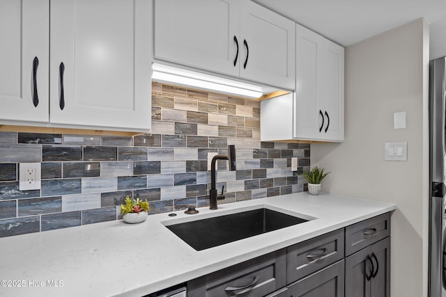 kitchen featuring light stone countertops, sink, backsplash, and white cabinets