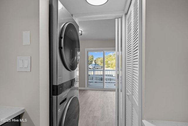 laundry room featuring stacked washer / drying machine and light hardwood / wood-style flooring