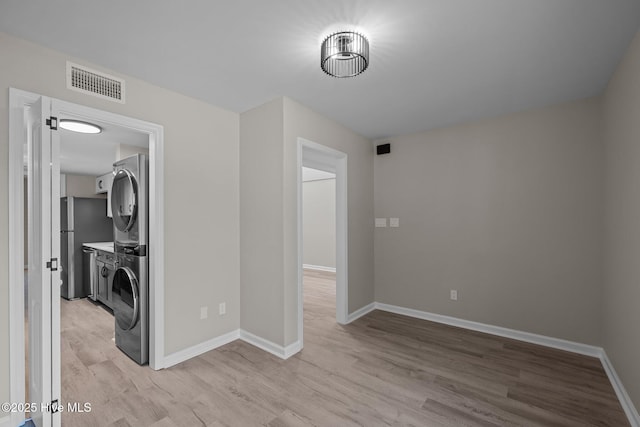 interior space with stacked washer / dryer and light hardwood / wood-style flooring