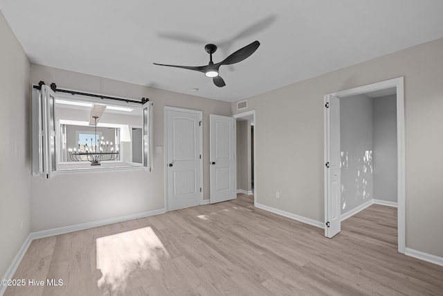 unfurnished bedroom featuring ceiling fan with notable chandelier and light hardwood / wood-style flooring