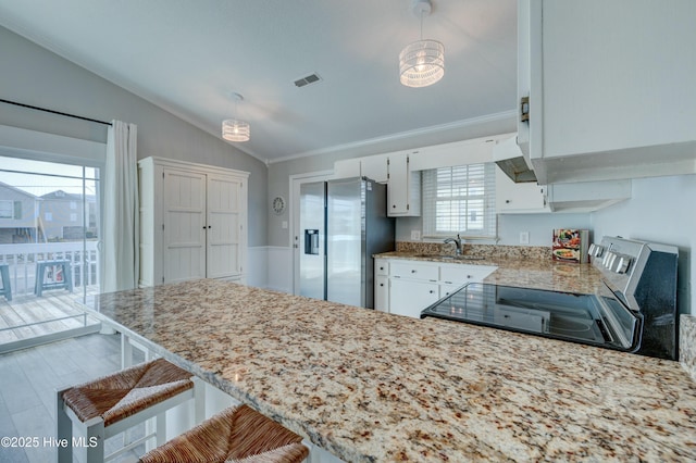 kitchen featuring hanging light fixtures, white cabinetry, range, and stainless steel fridge