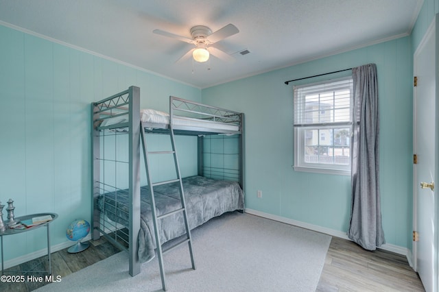 bedroom featuring hardwood / wood-style floors, crown molding, and ceiling fan