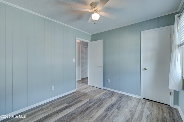 unfurnished bedroom with ceiling fan, ornamental molding, light hardwood / wood-style flooring, and a textured ceiling