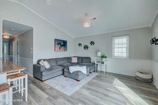 living room featuring ornamental molding, vaulted ceiling, and light hardwood / wood-style flooring