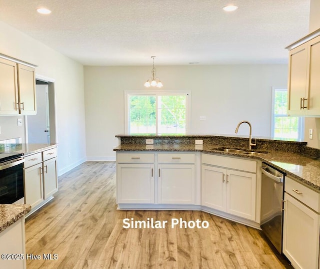 kitchen featuring stainless steel appliances, decorative light fixtures, dark stone countertops, a textured ceiling, and sink