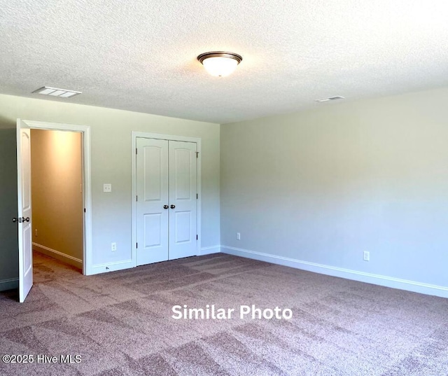 unfurnished bedroom with a textured ceiling, a closet, and carpet flooring