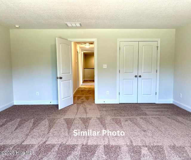 unfurnished bedroom with carpet, a closet, and a textured ceiling