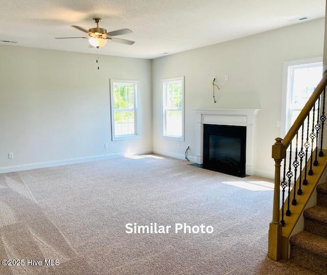 unfurnished living room featuring ceiling fan and carpet flooring