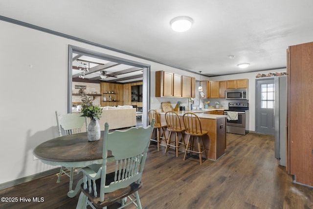 kitchen with ceiling fan, a kitchen bar, kitchen peninsula, dark hardwood / wood-style flooring, and stainless steel appliances