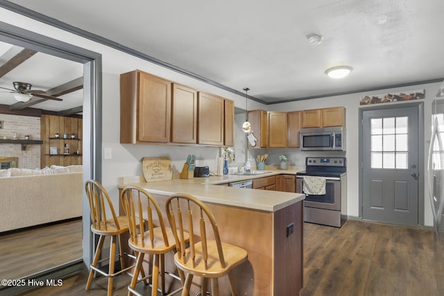 kitchen with appliances with stainless steel finishes, a kitchen breakfast bar, hanging light fixtures, dark hardwood / wood-style floors, and kitchen peninsula