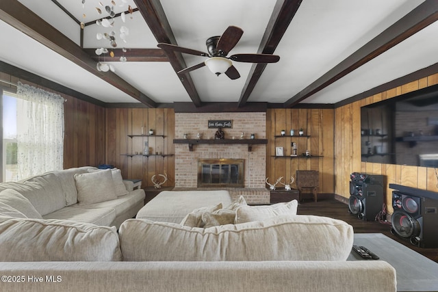 living room with wood-type flooring, ceiling fan, beam ceiling, a fireplace, and wood walls