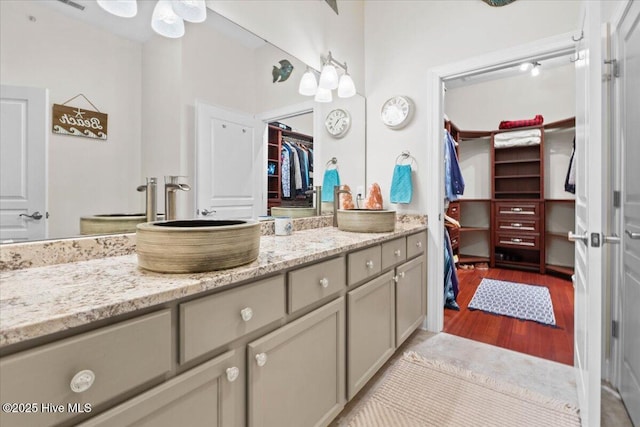 full bath with a walk in closet, wood finished floors, and vanity