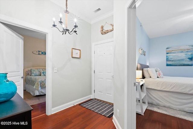 bedroom featuring dark wood-style flooring, visible vents, a notable chandelier, and baseboards