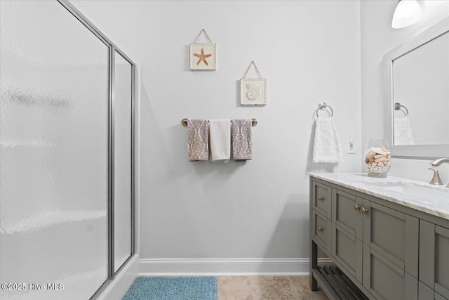 full bathroom featuring a shower stall, baseboards, and vanity