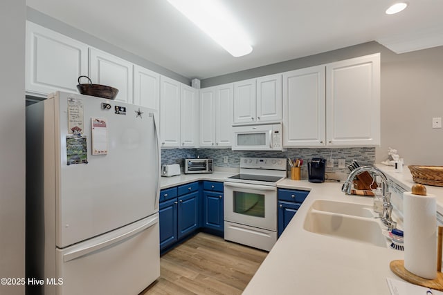 kitchen with white cabinetry, tasteful backsplash, white appliances, blue cabinets, and sink