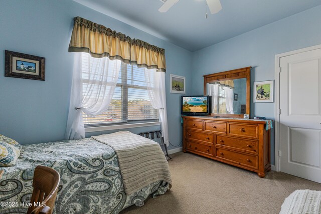 bedroom featuring ceiling fan, light colored carpet, and multiple windows