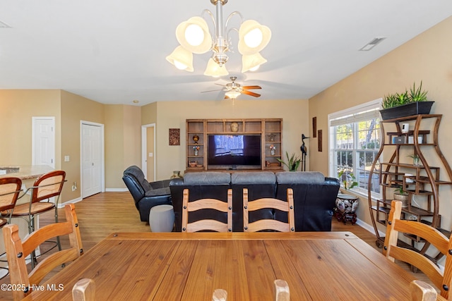 dining area featuring ceiling fan with notable chandelier and light wood-type flooring